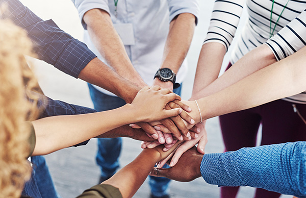 Closeup shot of a group of people joining their hands together in a huddle