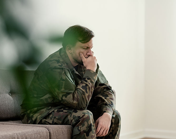 A male looking sad with his hand on his mouth, he is wearing an army uniform